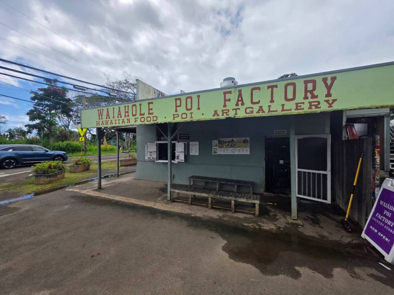 Small building with Waiāhole Poi Factory sign, green exterior, and a bench outside.