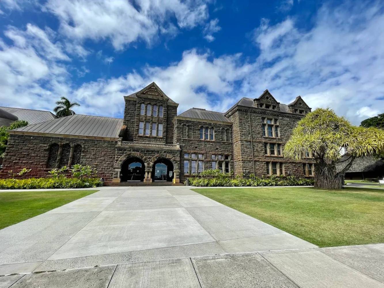 Historic stone building with a manicured lawn and blue sky.