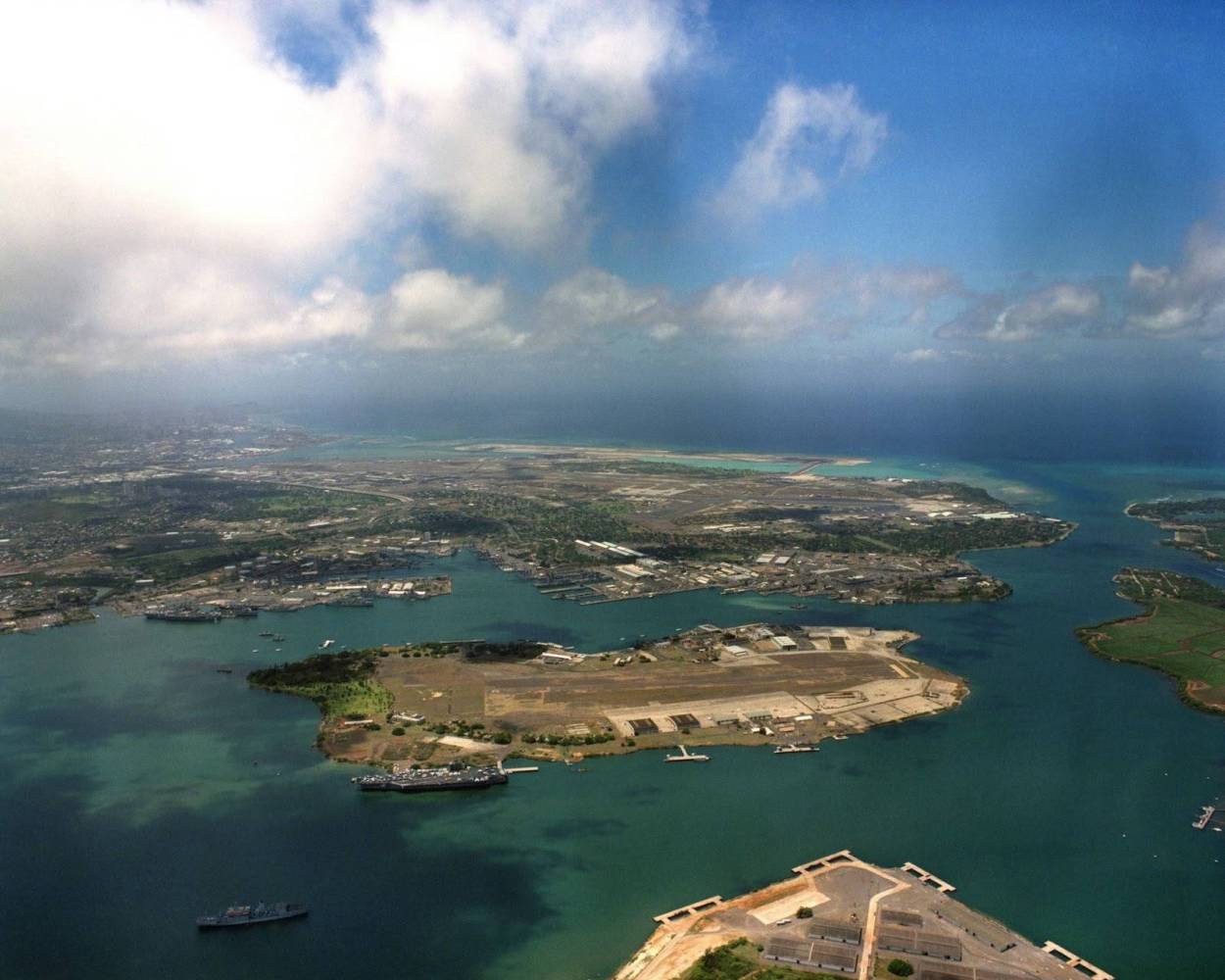 Aerial view of a coastal city with a harbor and scattered clouds in the sky.
