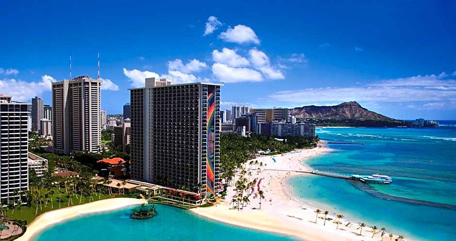 Urban skyline at Waikiki Beach with Diamond Head in the background under a blue sky.
