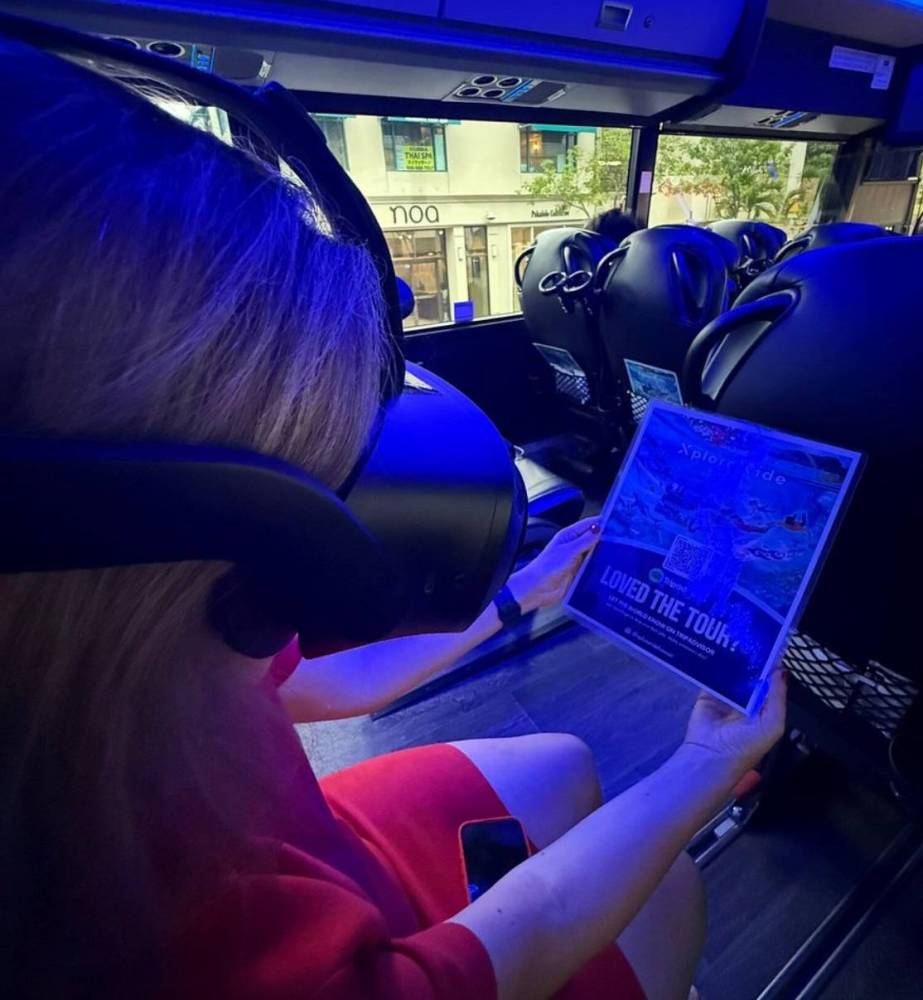 Person in red dress using VR headset, holding a brochure on a bus.