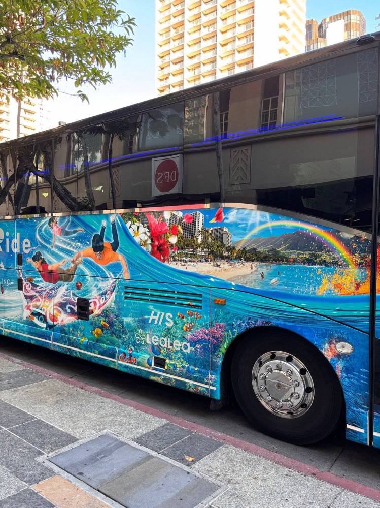 Colorful bus with beach and underwater murals parked on a city street.
