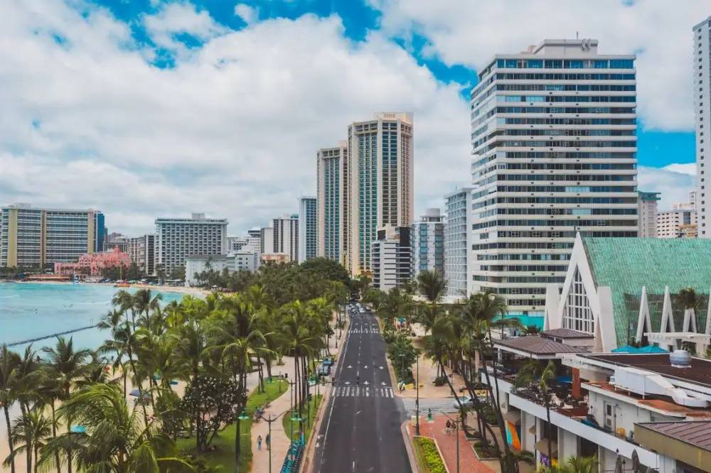Aerial view of a coastal city with tall buildings and palm-lined streets.