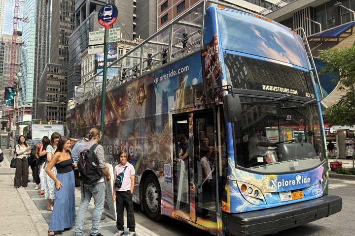 People boarding a colorful double-decker tour bus in a city.