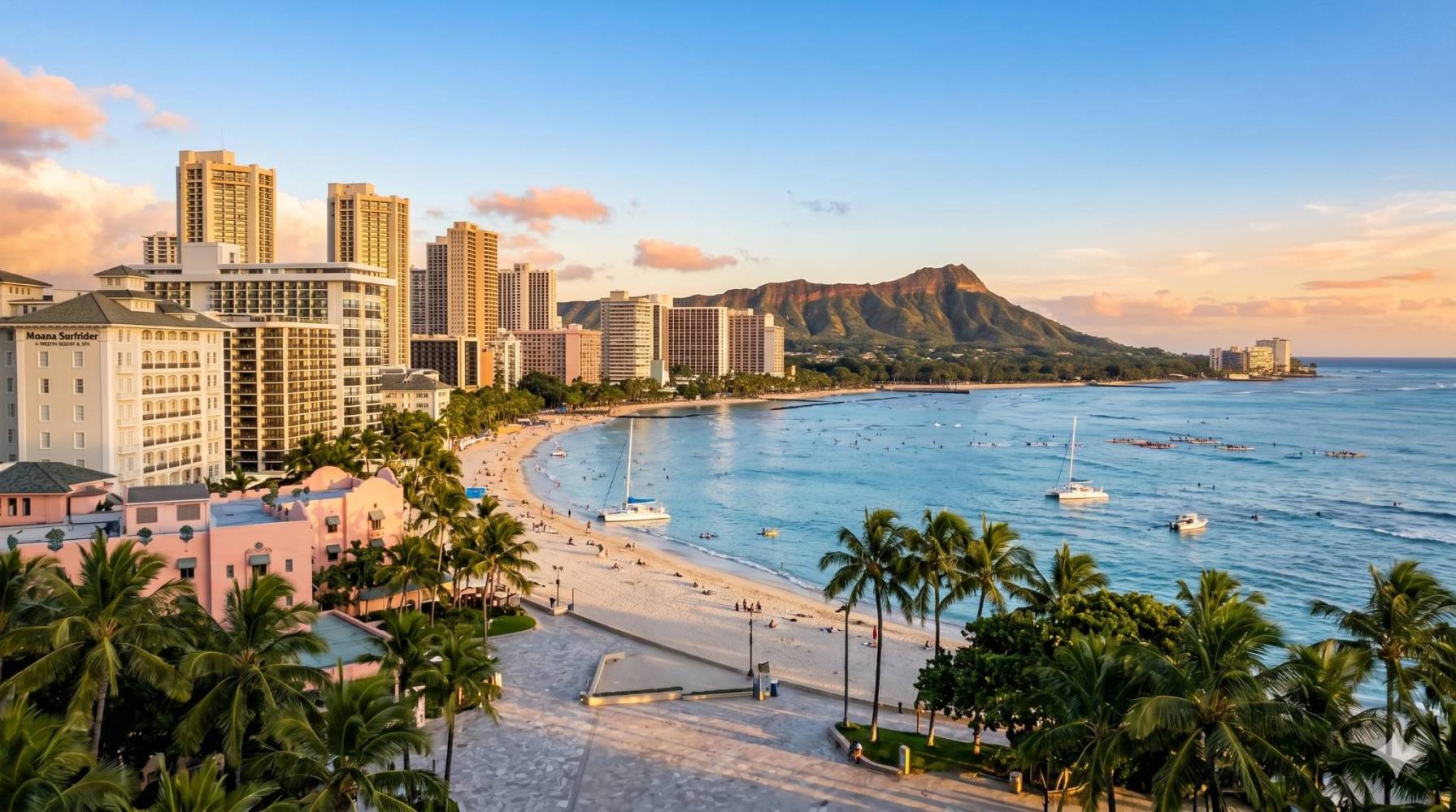 Aerial view of a beach with cityscape and a mountain in the background at sunset.