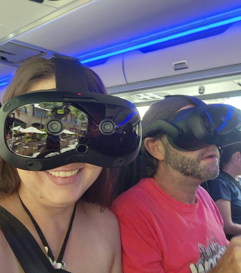 Two people wearing virtual reality headsets on a bus.