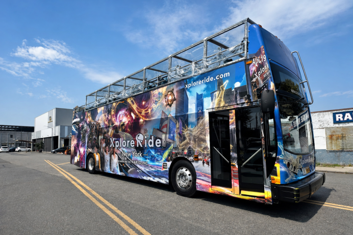 Colorful double-decker tour bus with open top parked on street.