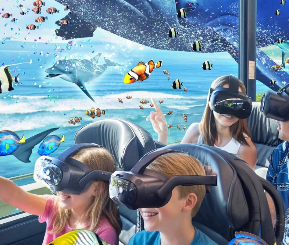 Kids wearing VR headsets on a bus, immersed in ocean life simulation with fish and whales.