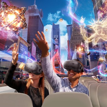 Two people with VR headsets on a bus, surrounded by virtual cityscape and magical elements.